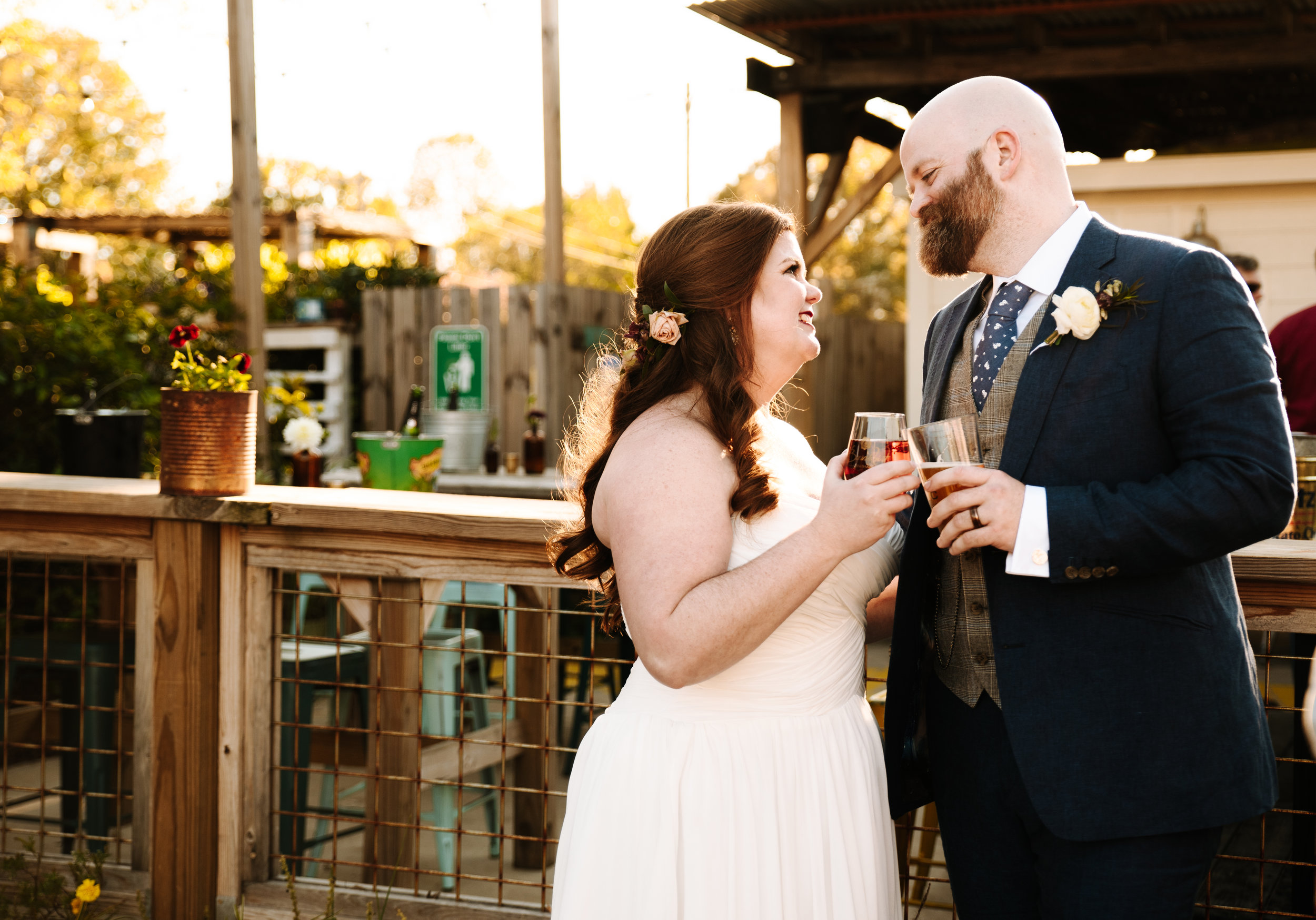 A couple looking at each other and holding glasses of alcohol at their wedding in Utah