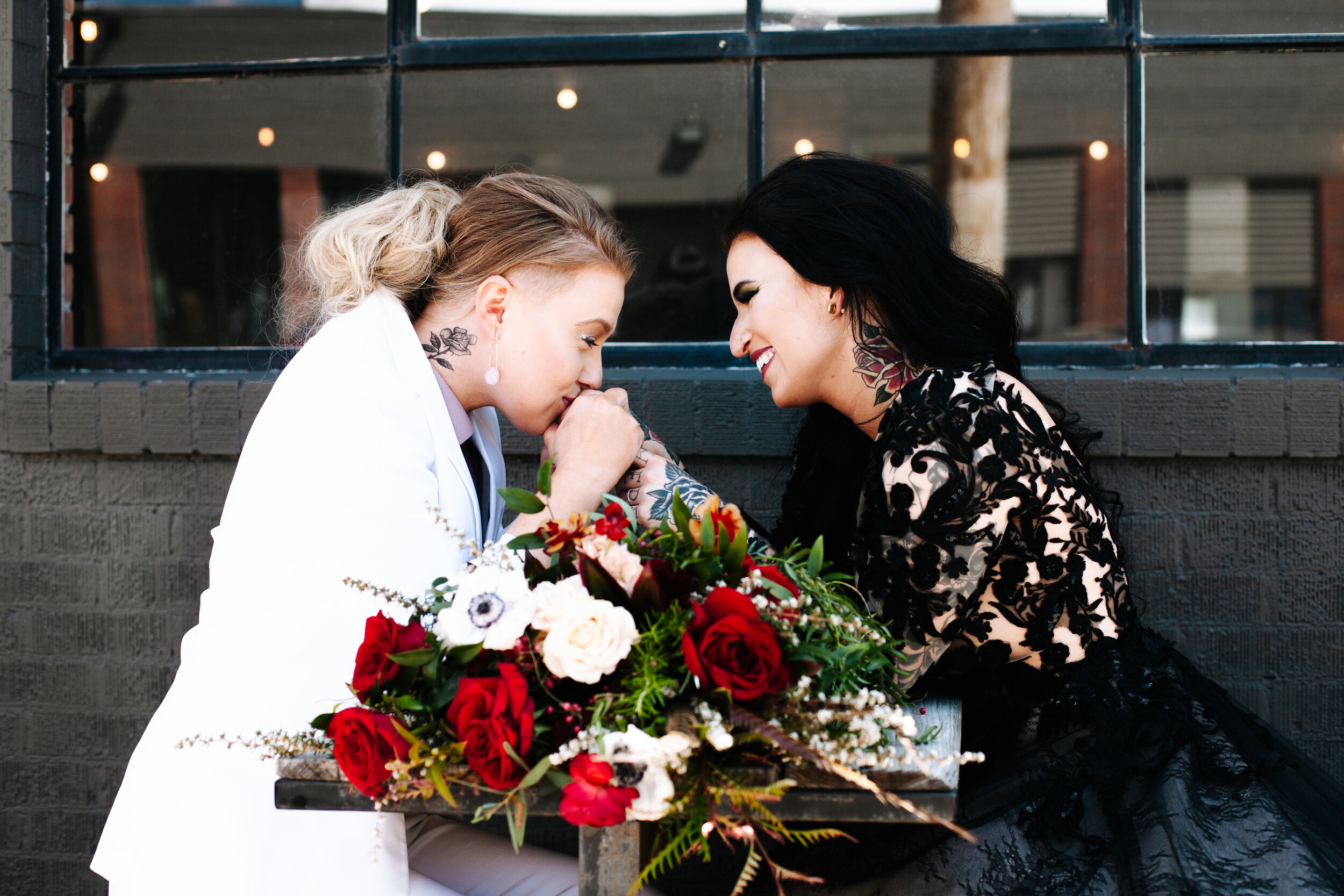 Lesbian couple sitting together holding hands outside of their wedding in Utah. 