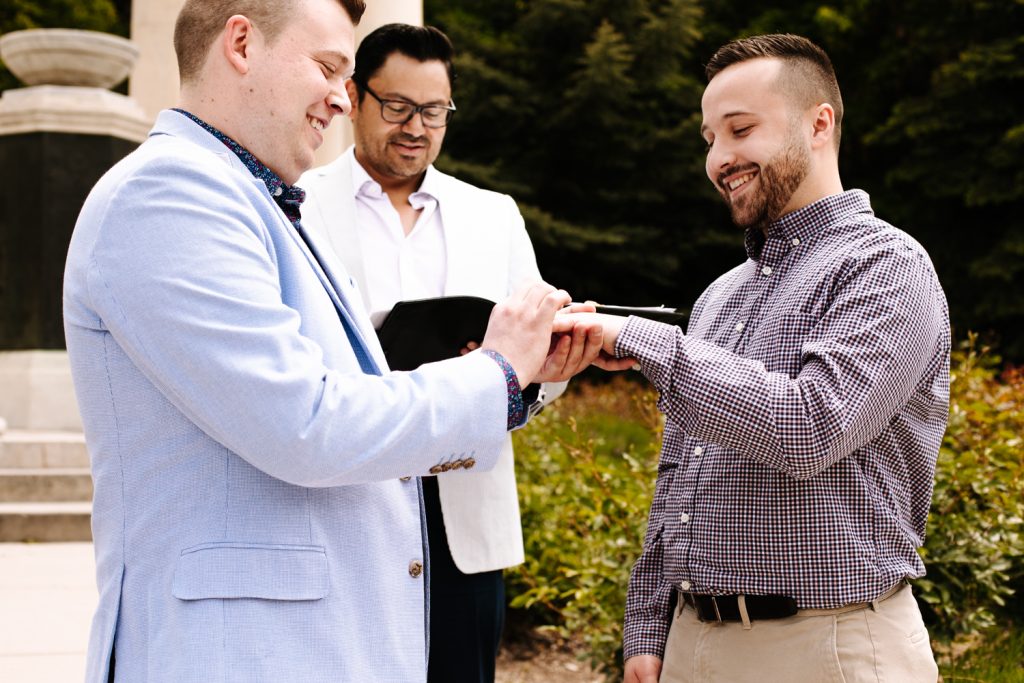 LGBTQ+ couple exchanging rings at their wedding near the Utah State Capitol Building.