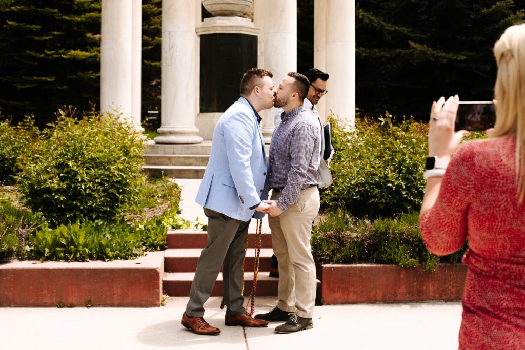 LGBTQ+ couple having their first kiss as a married couple at their wedding near the Utah State Capitol.