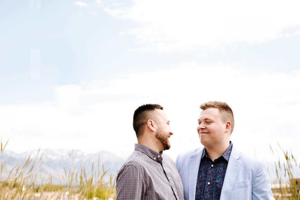 LGBTQ+ couple with masks at their wedding near the Utah State Capitol. Utah mountains can be seen in the background.