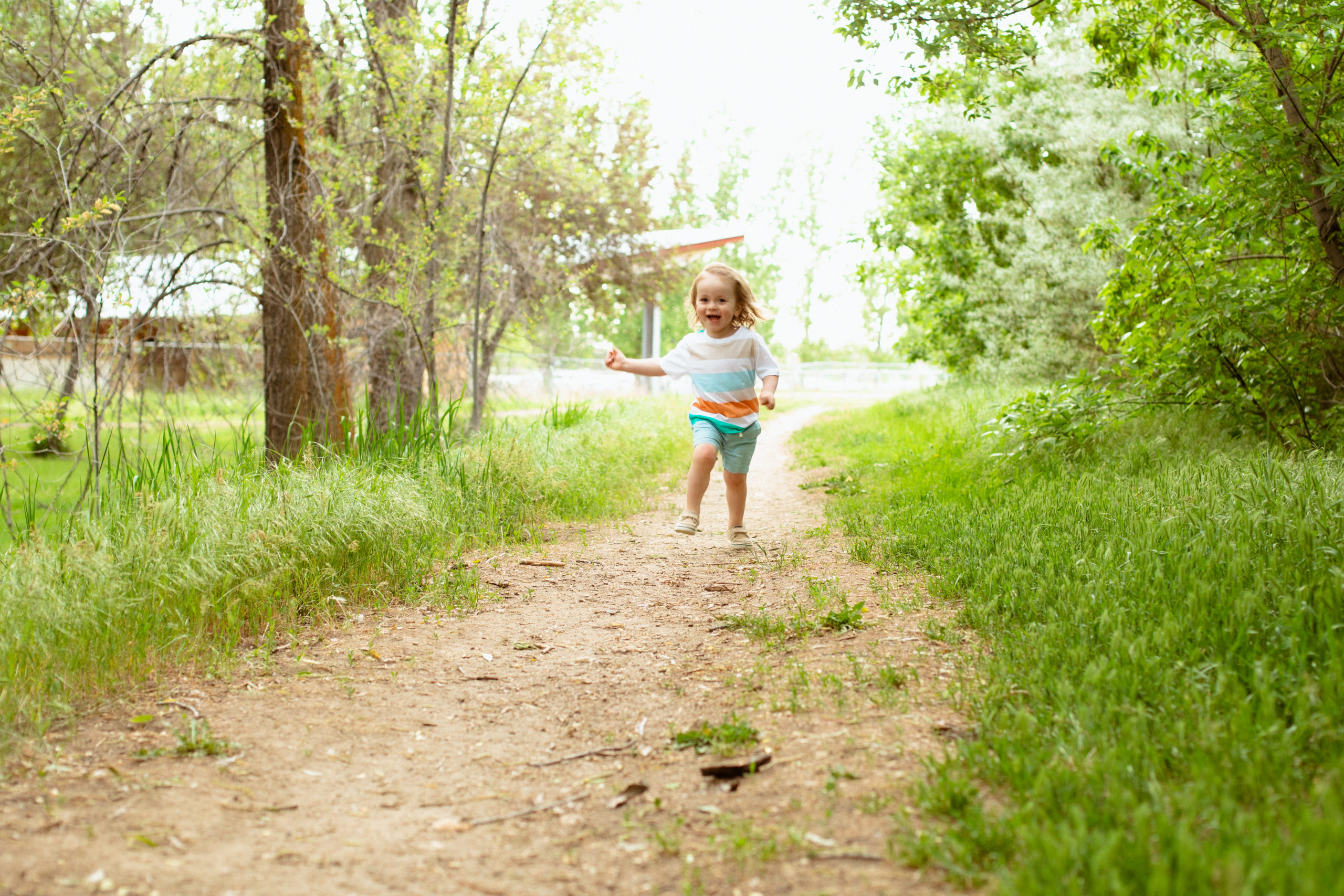 Toddler running and laughing on a path at Wheeler Farm during family photos.